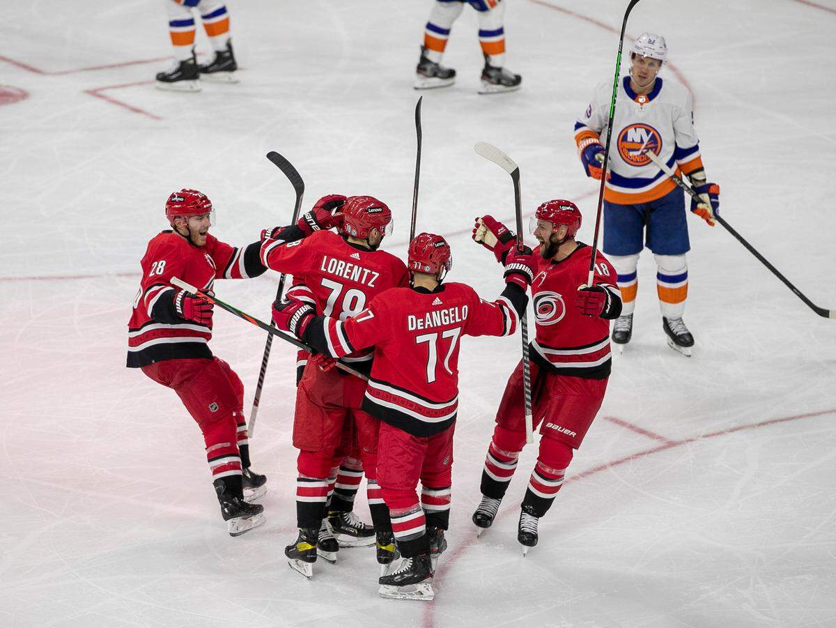 Carolina Hurricanes’ Jordan Martinook (48) is surrounded by teammates Ian Cole (28), Steven Lorentz (78), Tony DeAngelo (77) after scoring in the second period on Thursday, October 14, 2021 at PNC Arena in Raleigh, N.C.