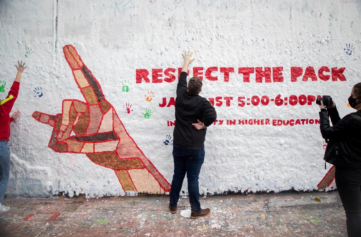 N.C. State student Coleman Simpson, center, adds his painted hand print to a mural in the Free Expression Tunnel during a protest of an internal investigation that did not result in the firing of Chadwick Seagraves, a university employee accused of Proud Boys membership and online harassment, on Tuesday, Jan. 19, 2021, in Raleigh, N.C.