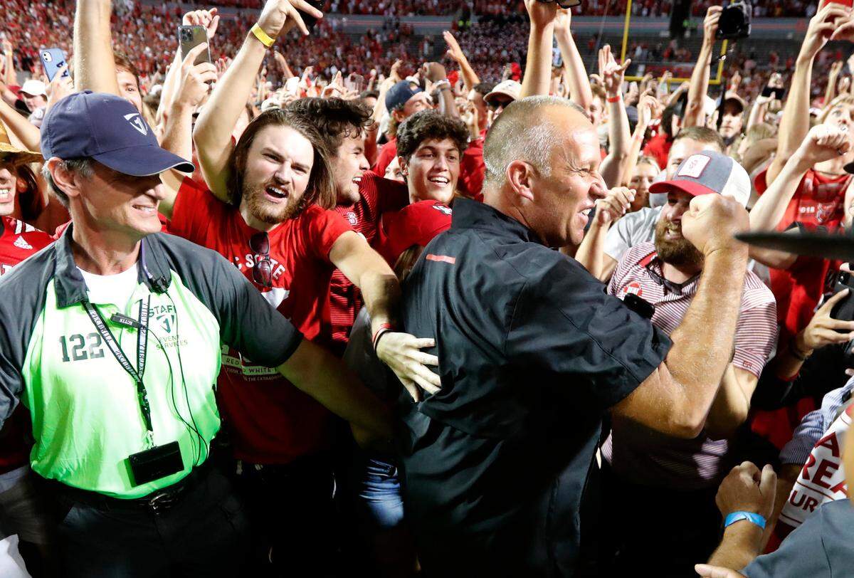 N.C. State head coach Dave Doeren celebrates with fans after N.C. State’s 27-21 overtime victory over Clemson at Carter-Finley Stadium in Raleigh, N.C., Saturday, Sept. 25, 2021.