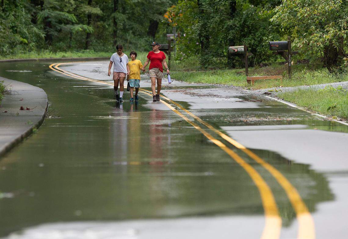 Mary Lindsley, right, walks with her children, Laali, 11, and Akaal, 8, along a partially flooded section of Umstead Drive as Tropical Storm Debby brings heavy rain to the Triangle on Thursday, Aug. 8, 2024, in Chapel Hill, N.C.