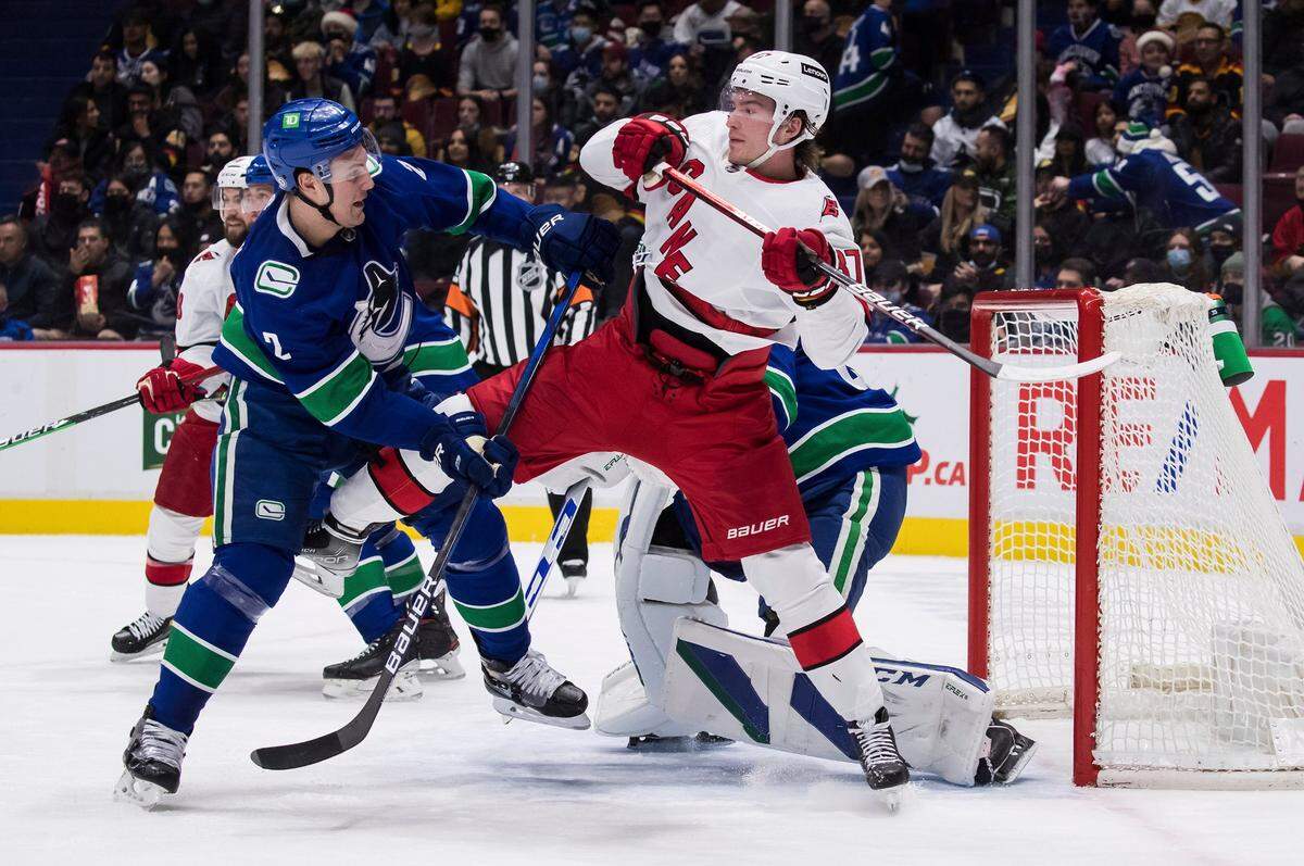 Vancouver Canucks’ Luke Schenn, left, checks Carolina Hurricanes’ Andrei Svechnikov, of Russia, during the first period of an NHL hockey game in Vancouver, British Columbia, Sunday, Dec. 12, 2021.