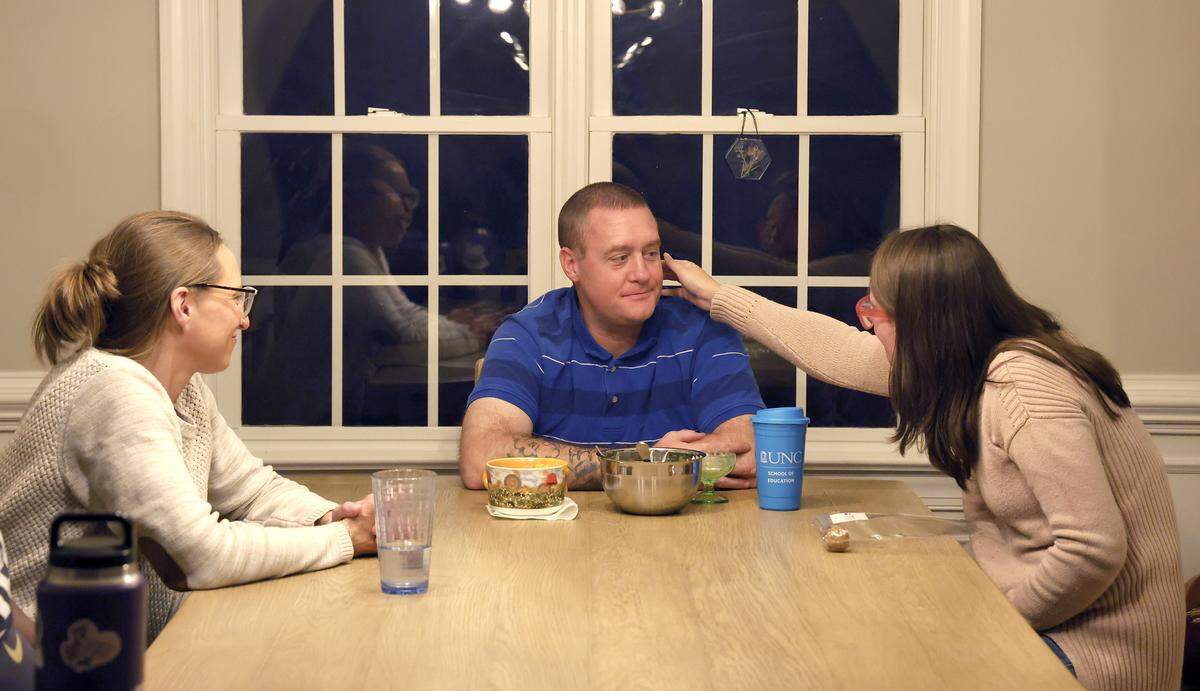 Lexi, right, sits with Krista and David Caraway after eating dinner at home.
