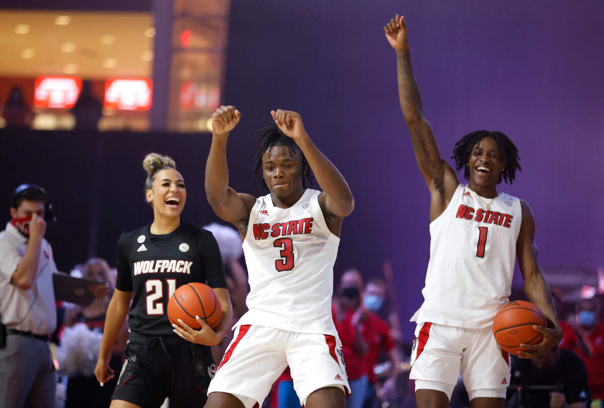 N.C. State’s Madison Hayes (21), Cam Hayes (3) and Dereon Seabron (1) celebrate after making a half-court shot during the Primetime with the Pack event at Reynolds Coliseum in Raleigh, N.C., Thursday, October 14, 2021.