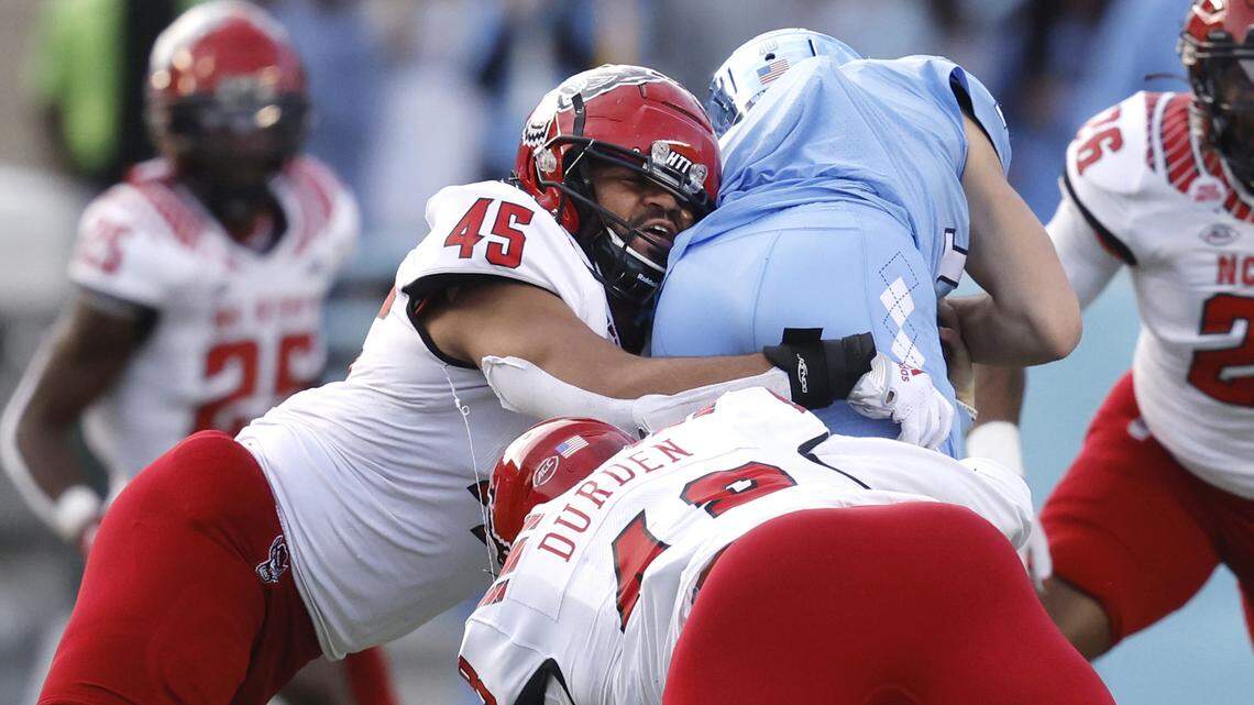 N.C. State’s Davin Vann (45) along with Cory Durden (48) tackle North Carolina quarterback Drake Maye during the Wolfpack’s game against UNC at Kenan Stadium in Chapel Hill in November 2022.