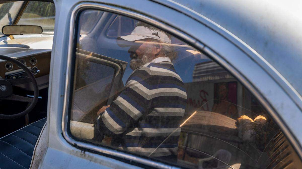 “Crazy Dale” Varnam is reflected in the window of one of this vintage Volkswagens on Thursday, February 22, 2024 in Varnamtown, N.C. Varnam has collected all types of vehicles, which are housed on 20 acres of his property.