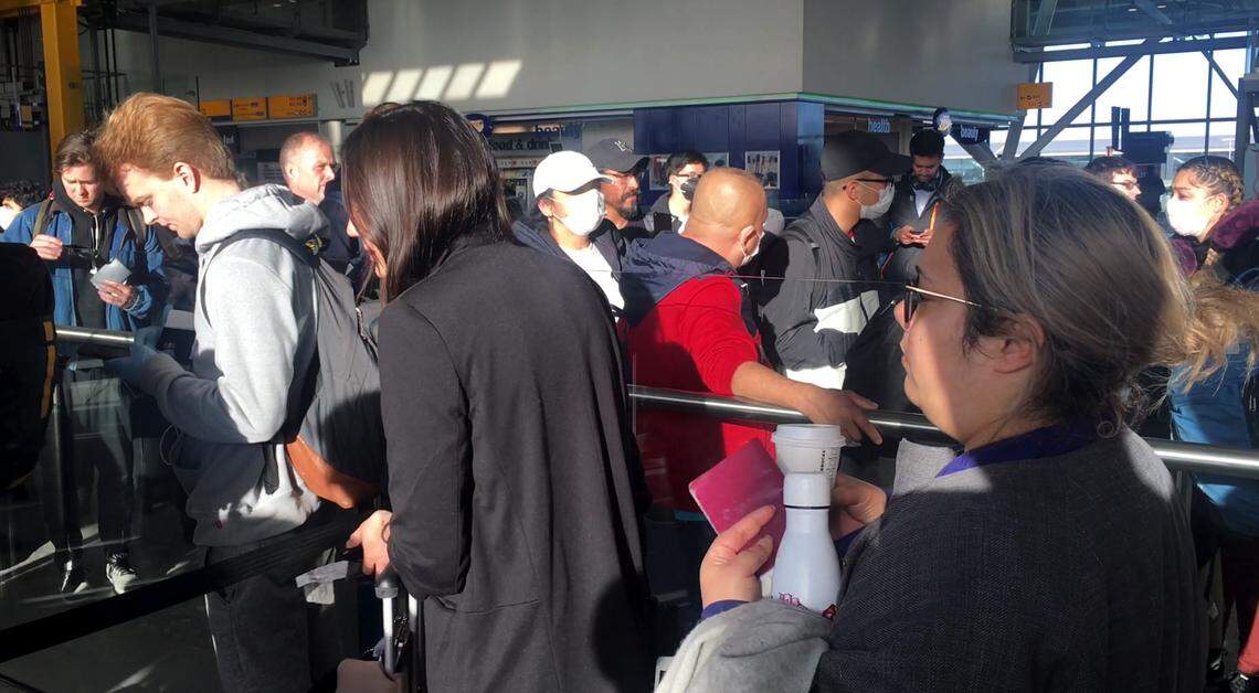 Travelers wait in line at Heathrow Airport to board their flight to the United States on Monday, March 16, 2020.