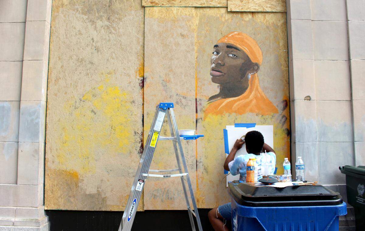 Joseph Campbell paints the boards covering the windows outside Apex Outfitters on June 8, 2020. Boarded up windows in downtown Raleigh were decorated in the weeks after the George Floyd protests on May 30 and 31, 2020.
