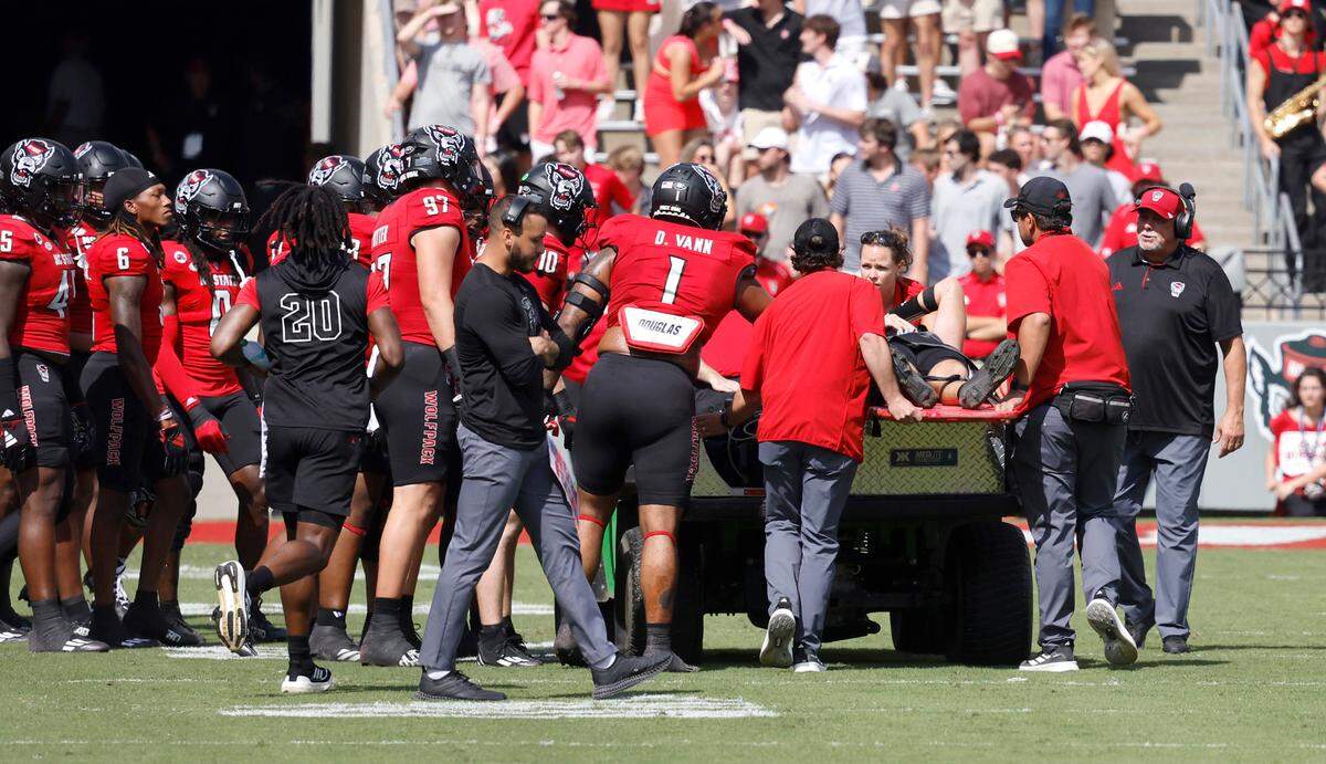 The team checks on N.C. State quarterback Grayson McCall as he is taken off the field after being injured during the first half of N.C. State’s game against Wake Forest at Carter-Finley Stadium in Raleigh, N.C., Saturday, Oct. 5, 2024.