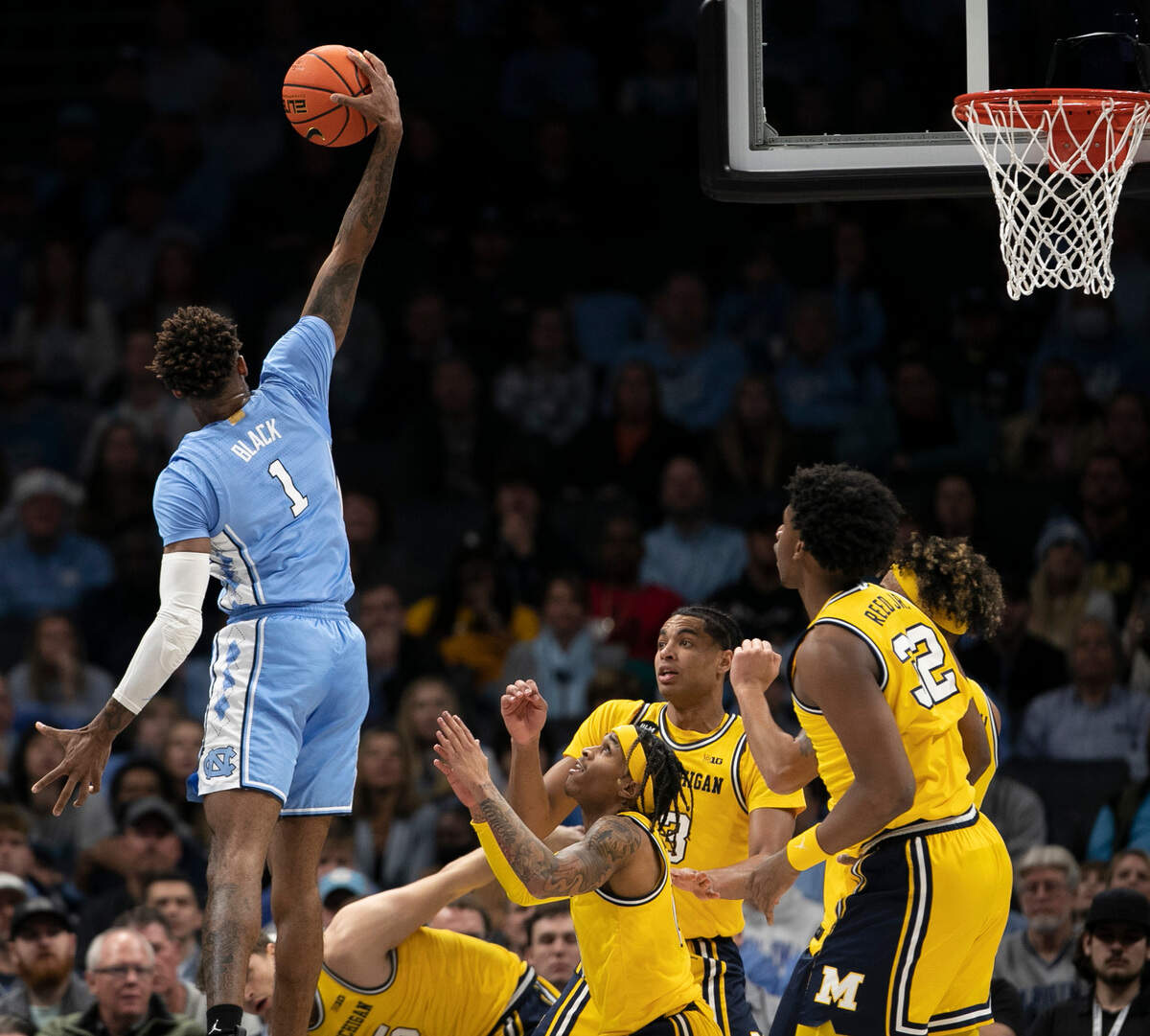 North Carolina’s Leaky Black (1) goes high over Michigan players to secure a defensive rebound in the first half on Wednesday, December 21, 2022 at the Spectrum Center in Charlotte, N.C. Black lead the Tar Heels with 10 rebounds.