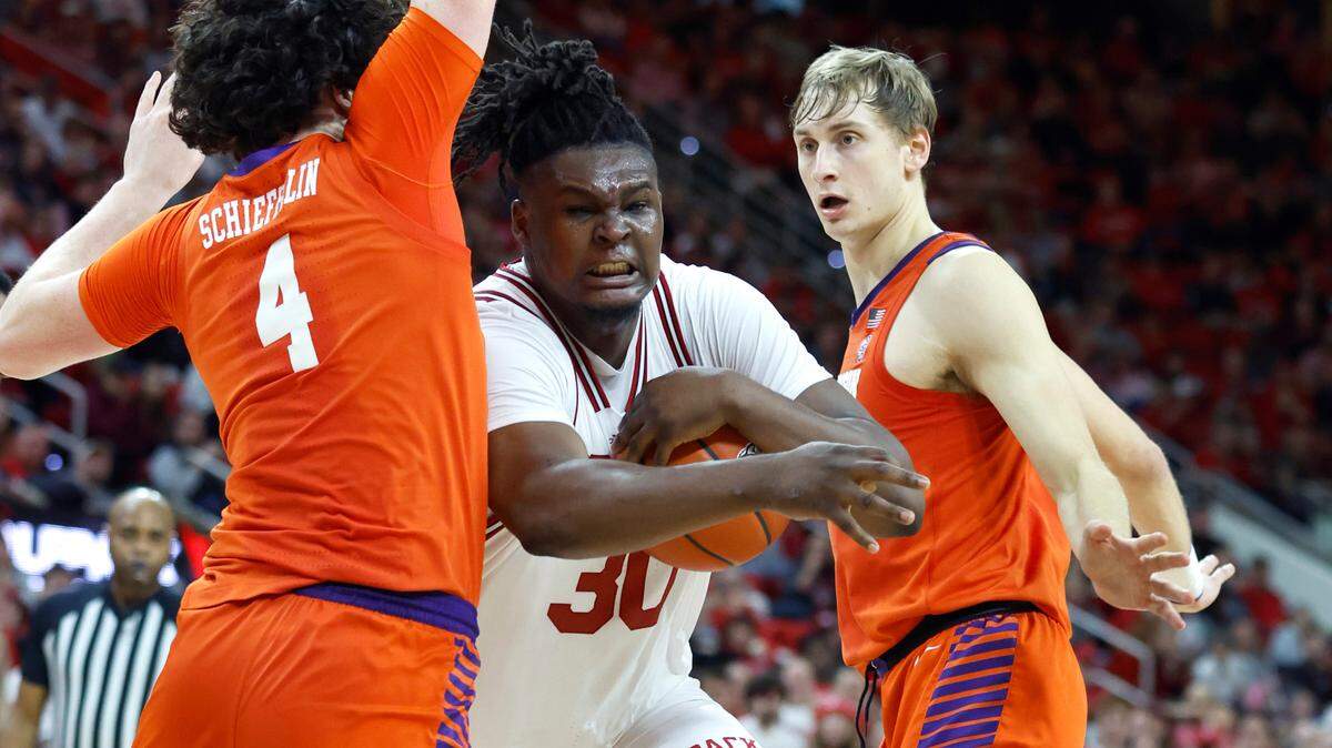 N.C. State’s D.J. Burns Jr. (30) drives between Clemson’s Ian Schieffelin (4) and Hunter Tyson (5) during the second half of Clemson’s 96-71 victory over N.C. State’s game at PNC Arena in Raleigh, N.C., Saturday, Feb. 25, 2023.