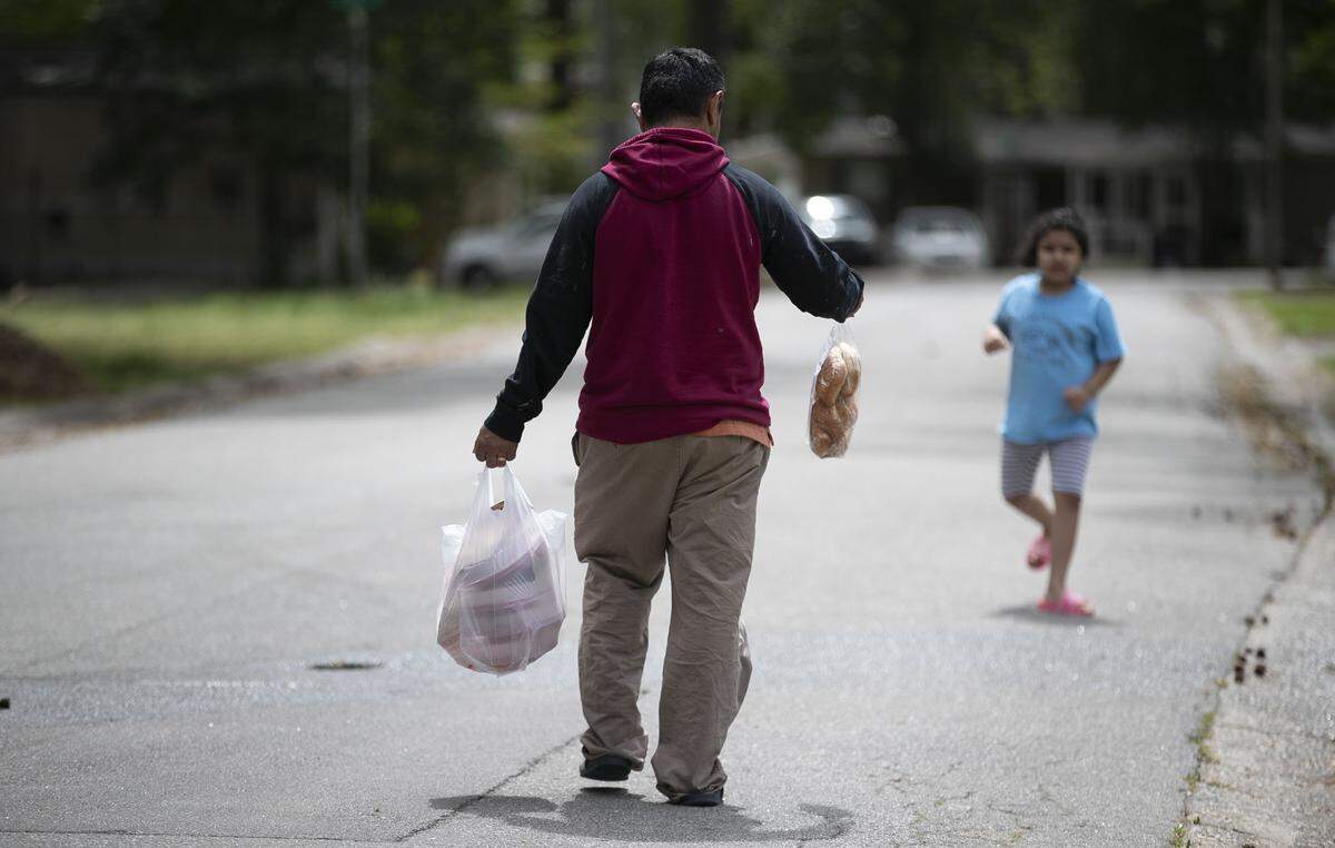 Residents in a mobile home community on Tate Street in Cary, N.C. head home after picking up meals from Cary United Methodist Church on Wednesday, April 1, 2020.