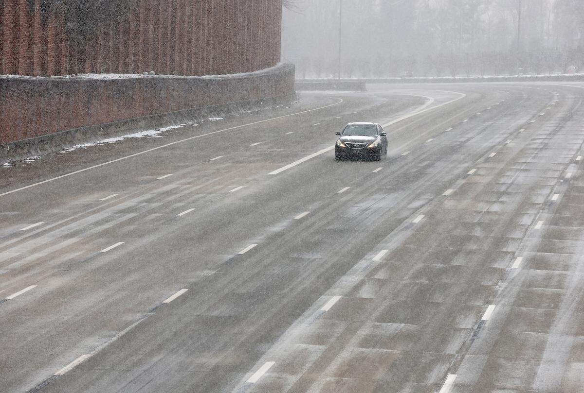 A vehicle travels along Interstate-85 as snow falls in Durham, N.C. on Wednesday, Feb. 19, 2025.