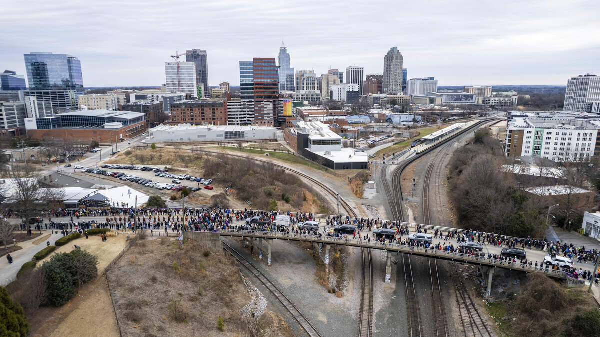 A procession of Buddhist monks walks across Boylan Bridge in downtown Raleigh, followed by hundreds of well-wishers on Saturday, Jan. 24, 2026. The monks are making a 2,300-mile pilgrimage from Texas to Washington, D.C., as part of the Walk for Peace, an effort to promote peace, compassion and national unity.