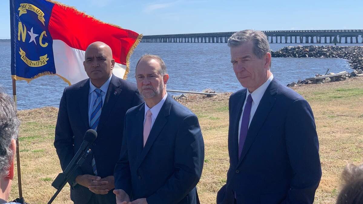 Federal Highway Administrator Shailen Bhatt, left, N.C. Department of Transportation Secretary Eric Boyette, center, and Gov. Roy Cooper speak to reporters at the western end of the Alligator River Bridge in Tyrrell County on March 9, 2023. Boyette will retire effective Oct. 1.