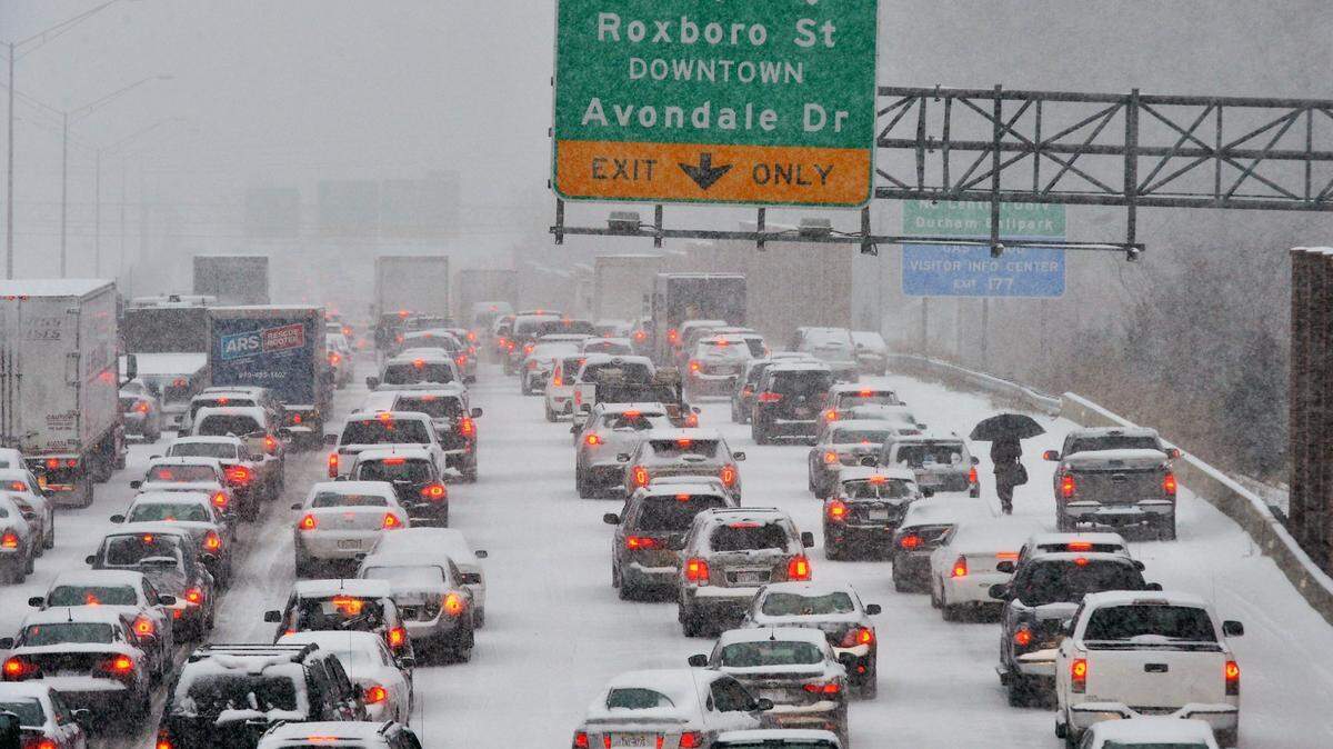 A motorist who abandoned their vehicle walks through traffic stopped on northbound I-85 in Durham, NC Wednesday Feb. 12, 2014. The Triangle had its biggest storm in several years and most major roads in the area were snarled.