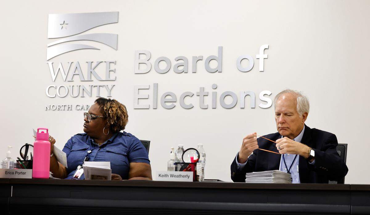 Wake County Board of Elections chair Erica Porter and Board of Elections member Keith Weatherly inspect absentee ballots during a board meeting at the Wake County Board of Elections Operations Center in Raleigh, N.C., Tuesday, Oct. 8, 2024.