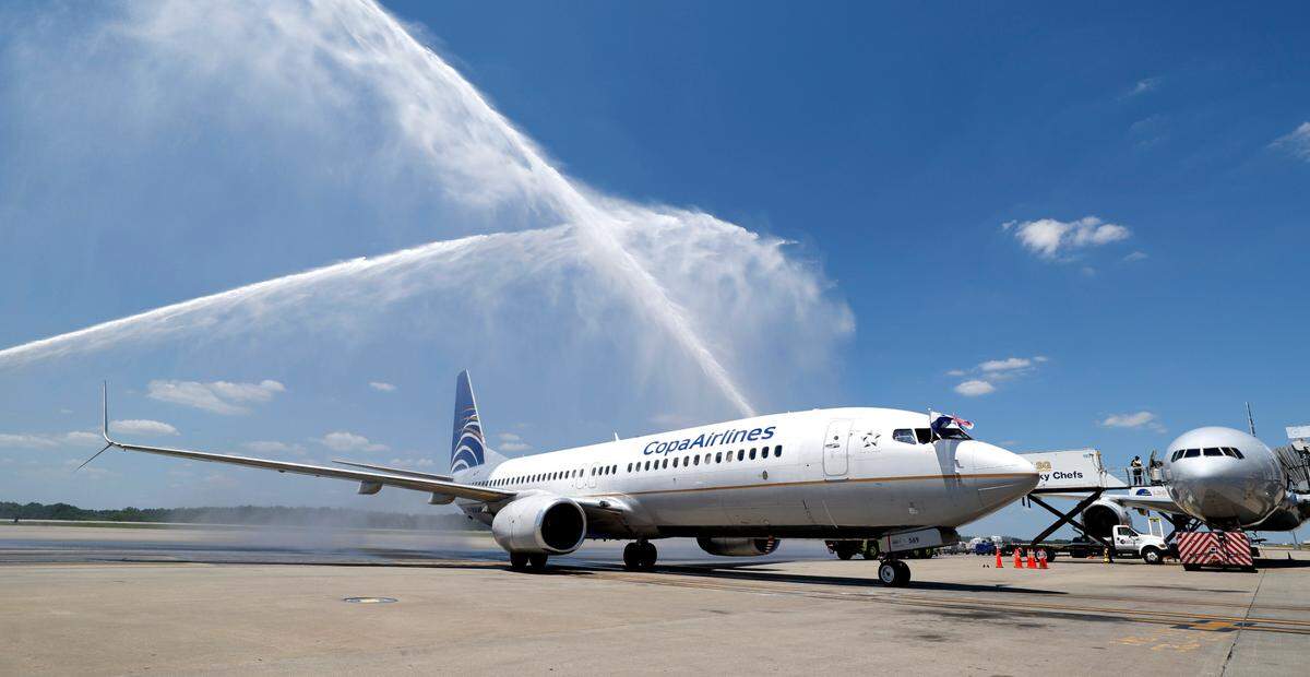 The flight crew of the inaugural Copa Airlines flight from Panama City, Panama to Raleigh-Durham International Airport wave the Panamanian and American flags as they get a water cannon salute as they arrive at their gate Friday, June 21, 2024.