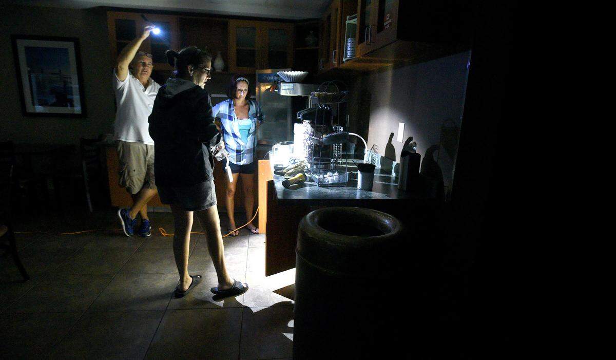 Mitchell Floor (left) holds a flashlight as Comfort Suites general manager Beth Bratz (center) and employee Dee Branch go to make coffee as Hurricane Florence rages in Wilmington, N.C. Thursday Sept. 14, 2018.  The area lost power around 4 a.m. and the facility was  running small lights, phone chargers and the coffee machine on a generator.