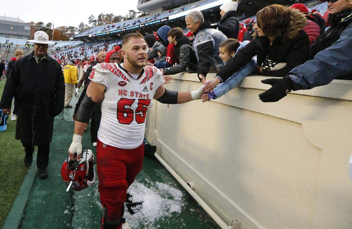 N.C. State center Garrett Bradbury (65) greets fans after the Wolfpack’s 34-28 overtime victory over UNC at Kenan Stadium in Chapel Hill, N.C., Saturday, Nov. 24, 2018.