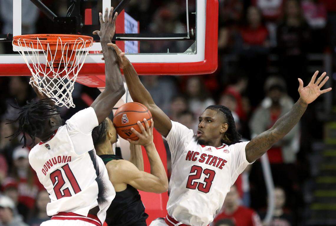 N.C. State’s Ebenezer Dowuona and Greg Gantt contest a shot by Miami’s Isaiah Wong during the second half of the Wolfpack’s 83-81 win over Miami at PNC Arena on Saturday, Jan. 14, 2023, in Raleigh, N.C.