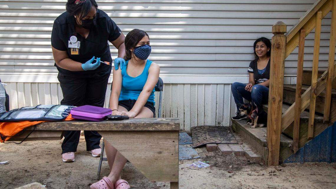 Dr. Nerissa Price administers a COVID-19 vaccine to Kelsey Fores, 12, as volunteer canvassers went door to door offering vaccines at a Raleigh mobile home park in Raleigh Friday July 23, 2021. Using Census tract data to identify low vaccination areas in Wake County, outreach teams are working to increase vaccine rates in communities with low vaccination rates.