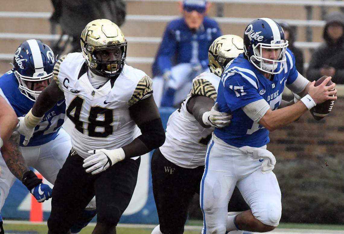 Wake Forest defensive lineman Willie Yarbary (48) and teammate defensive lineman Carlos Basham Jr. (18) go to sack Duke quarterback Daniel Jones (17) in the first quarter of play at Wallace Wade Stadium, Saturday, Nov. 24, 2018 in Durham, N.C.