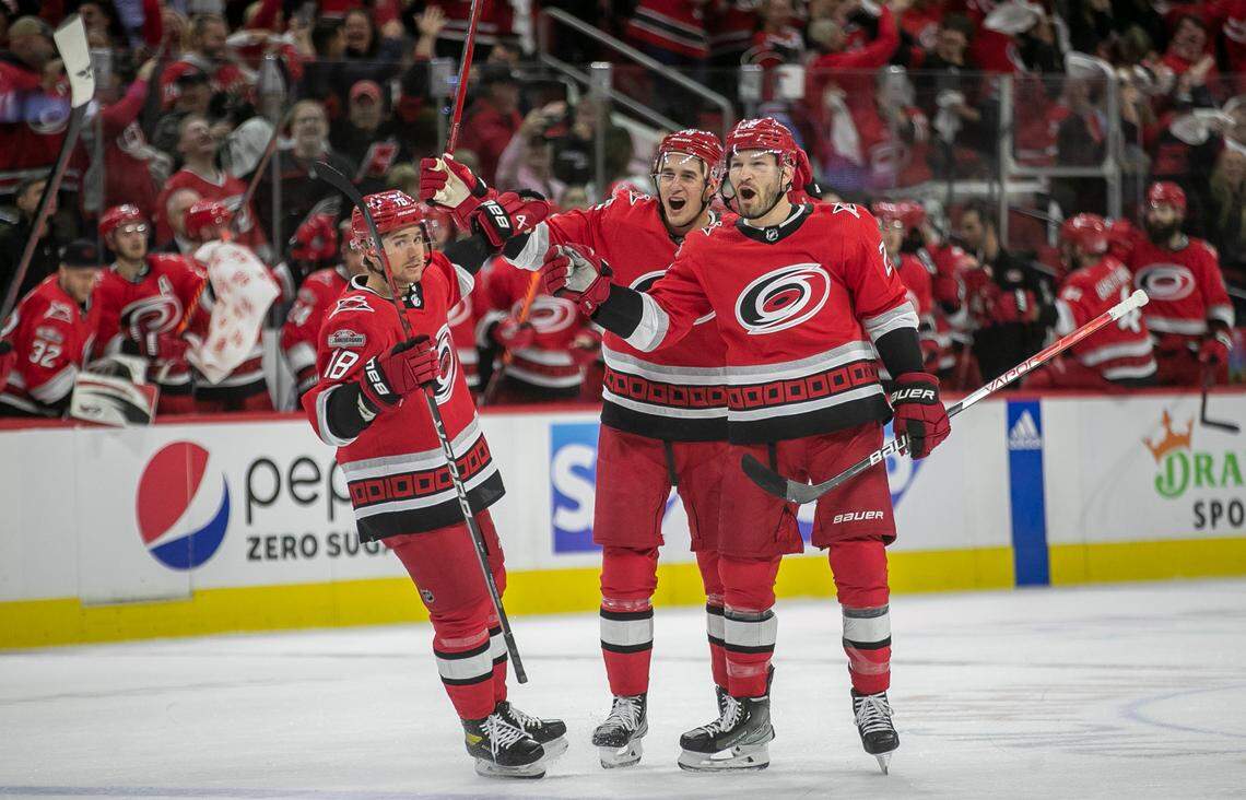 The Carolina Hurricanes Brett Pesce (22) celebrates with teammates Jack Drury (18) and Brady Skjei (76) after scoring on New Jersey Devils goalie Akira Schmid (40) in the first period during Game 1 of their second round Stanley Cup playoff series on Wednesday, May 3, 2023 at PNC Arena in Raleigh, N.C.