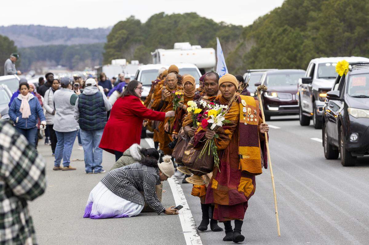 A procession of Buddhist monks walks along U.S. Highway 64 near Wilsonville on Friday, Jan. 23, 2026, as thousands of onlookers line the highway to welcome them. The monks are making a 2,300-mile pilgrimage from Texas to Washington, D.C., as part of the Walk for Peace, an effort to promote peace, compassion and national unity.