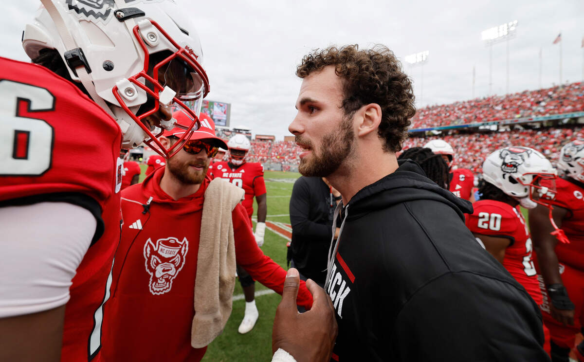 Former N.C. State linebacker Payton Wilson talks with quarterback CJ Bailey (16) after Wilson was inducted into the Ring of Honor during the Wolfpack’s game against Stanford at Carter-Finley Stadium in Raleigh, N.C., Saturday, Nov. 2, 2024.