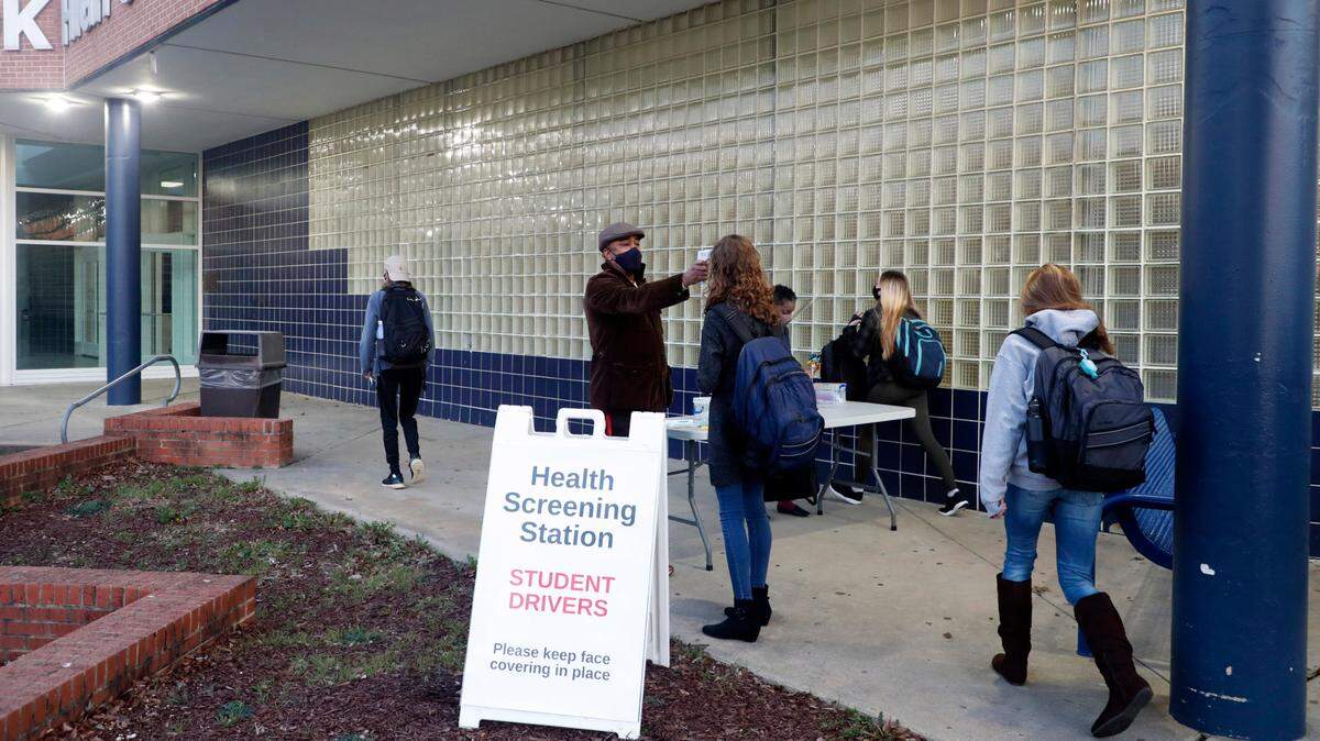 Students arriving at Millbrook High School in Raleigh, N.C. have their temperature taken and are asked health questions before entering the building on Feb. 17, 2021. It was the first day of face-to-face classes since March 2020 for Wake County high school students.