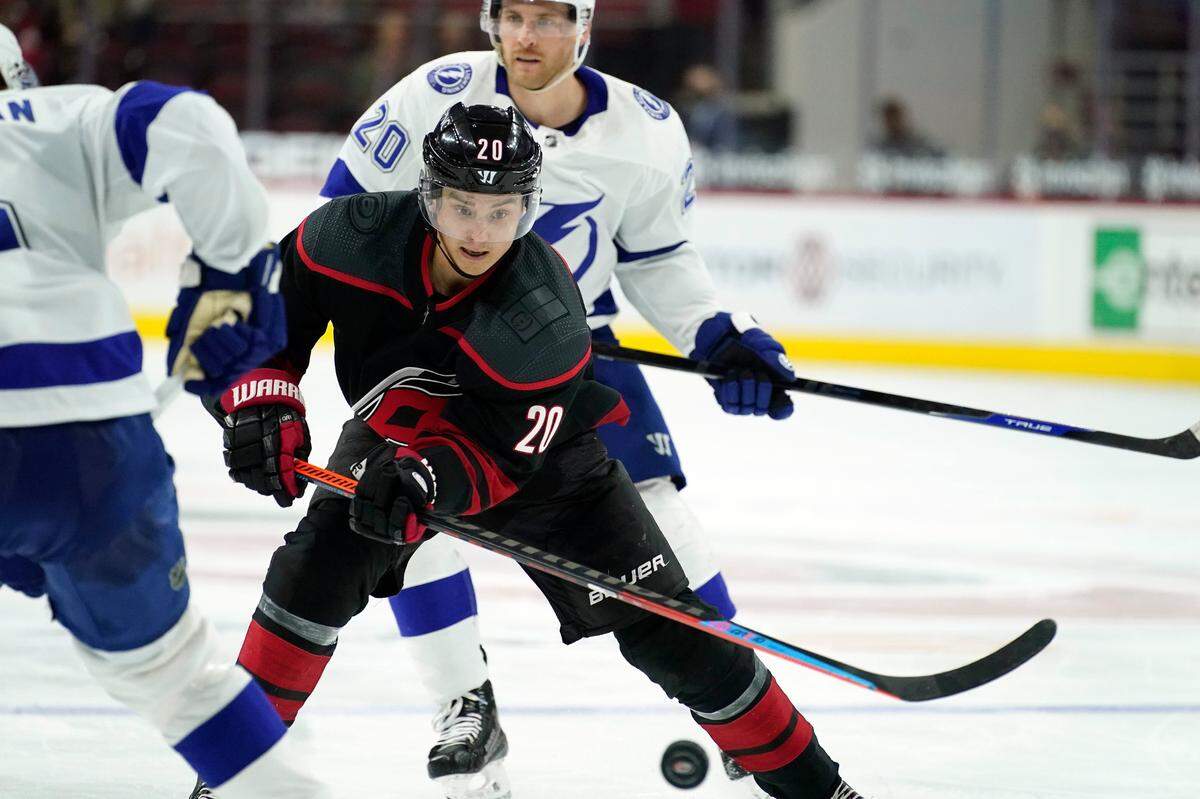 Carolina Hurricanes right wing Sebastian Aho, front, of Finland, controls the puck while Tampa Bay Lightning center Blake Coleman pursues during the second period of an NHL hockey game in Raleigh, N.C., Saturday, March 27, 2021. (AP Photo/Gerry Broome)