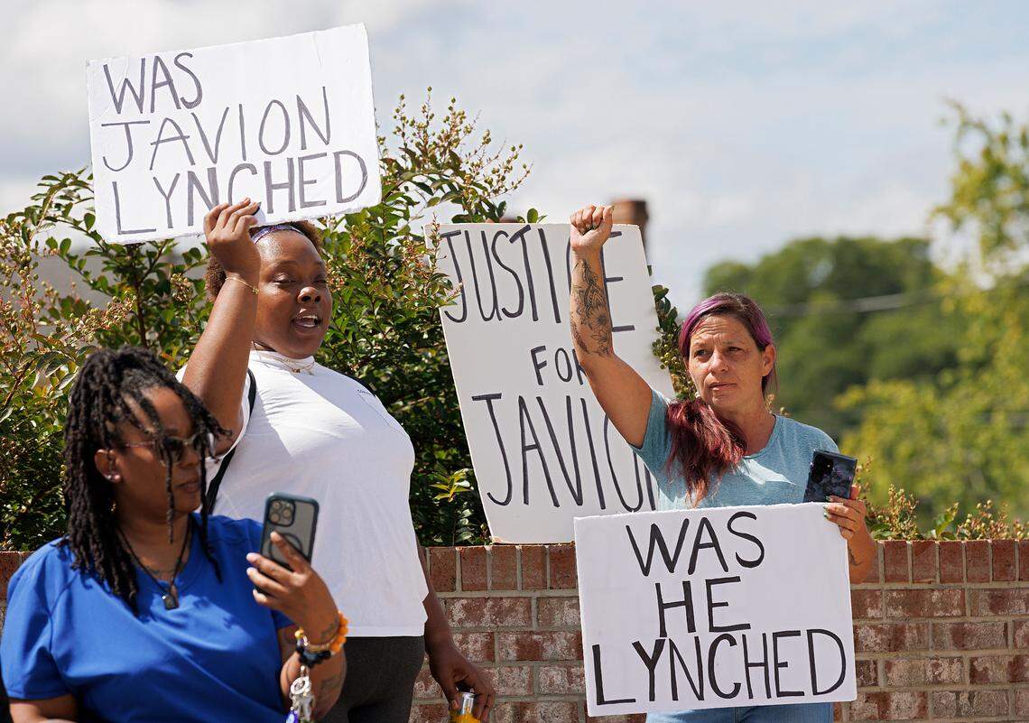 Cherry Brandon, center, and Sarah Pitkin, right, hold signs prior to a press conference held by attorneys and the family of Javion Magee in front of the Vance County Courthouse in Henderson, N.C. on Wednesday, Sept. 18, 2024. Magee, 21, was found dead by a tree with a rope around his neck in Henderson on Sept. 11.
