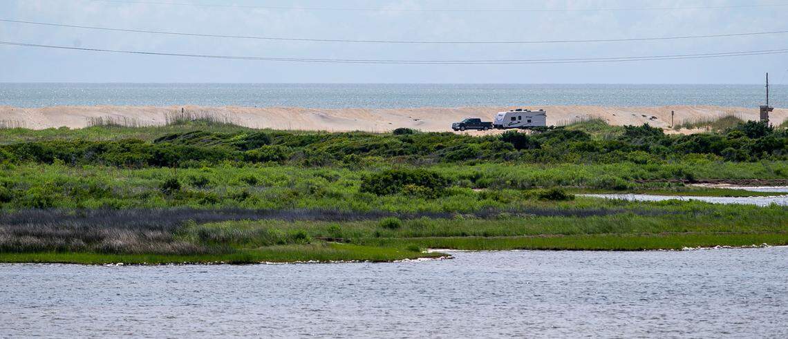 A vehicle pulls a camper along NC 12 in a narrow place between the Atlantic Ocean and the Pamlico Sound on Wednesday, June 30, 2021 in Rodanthe, N.C. This area, called the ‘S Curves’, is one of the hot spots along the highway that is often subjected to erosion and flooding. A new bridge is currently being constructed around the troubled spot to enable safe travel.