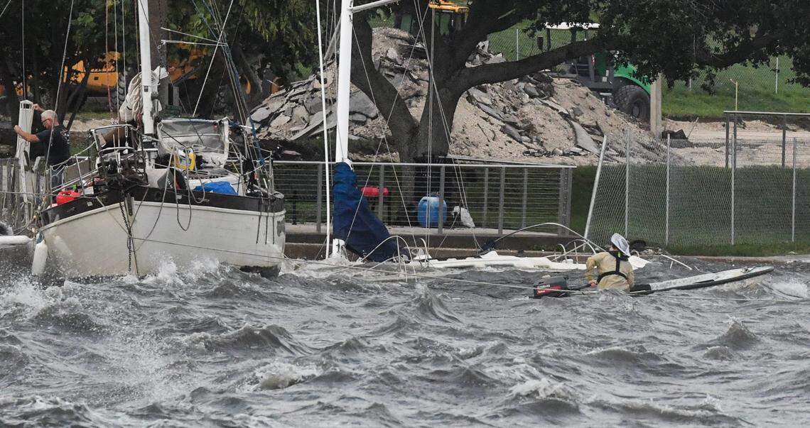 Two men brave the winds and heavy surf to try and secure a boat along the seawall Thursday, September 26, 2024.