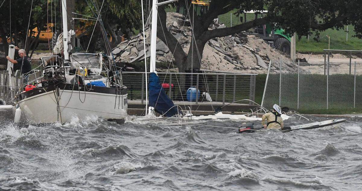 Two men brave the winds and heavy surf to try and secure a boat along the seawall Thursday, September 26, 2024.