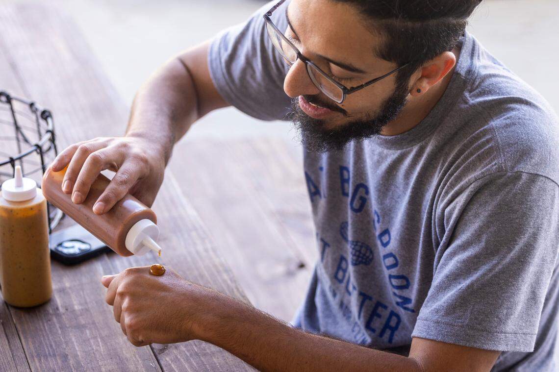 Shak Khavarian samples sauces during the opening of Longleaf Swine in Raleigh Friday, Nov. 4, 2022.