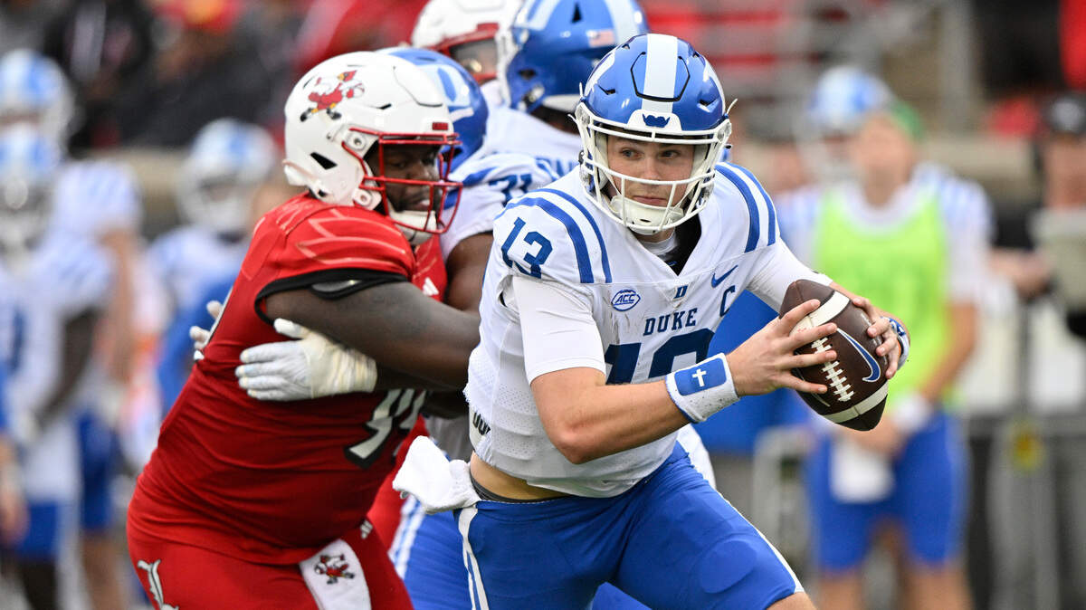 Duke Blue Devils quarterback Riley Leonard (13) scrambles away from Louisville Cardinals defensive lineman Dezmond Tell (99) during the second quarter at L&N Federal Credit Union Stadium.