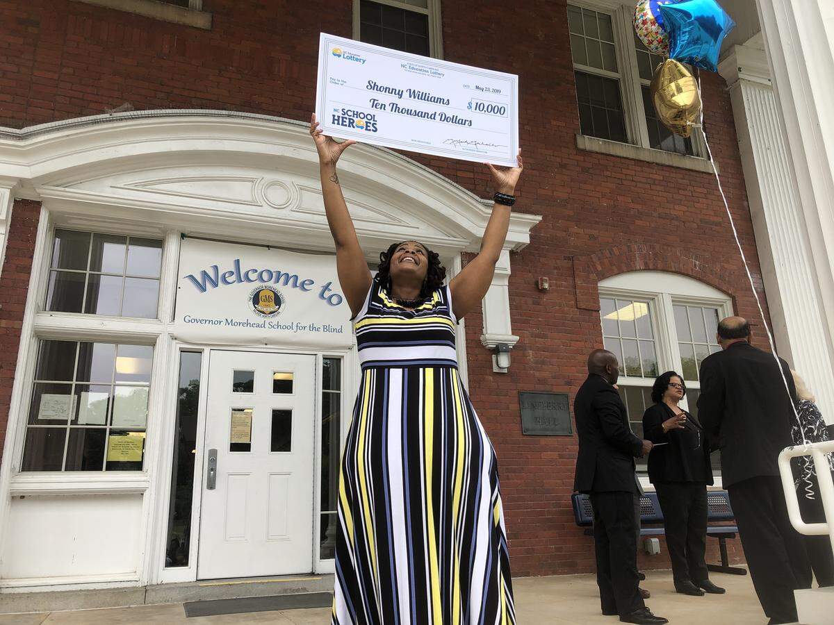 Shonny Willams, a school social worker at the Governor Morehead School For The Blind, holds up the $10,000 check she received on May 23,2019 in Raleigh after being named one of the 10 winners of the N.C. Education Lottery’s N.C. School Heroes program.