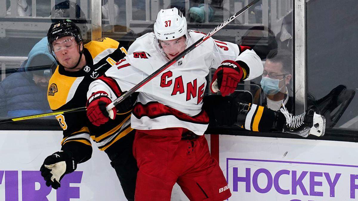 Carolina Hurricanes right wing Andrei Svechnikov (37) checks Boston Bruins defenseman Charlie McAvoy into the boards during the second period of an NHL hockey game, Thursday, Feb. 10, 2022.