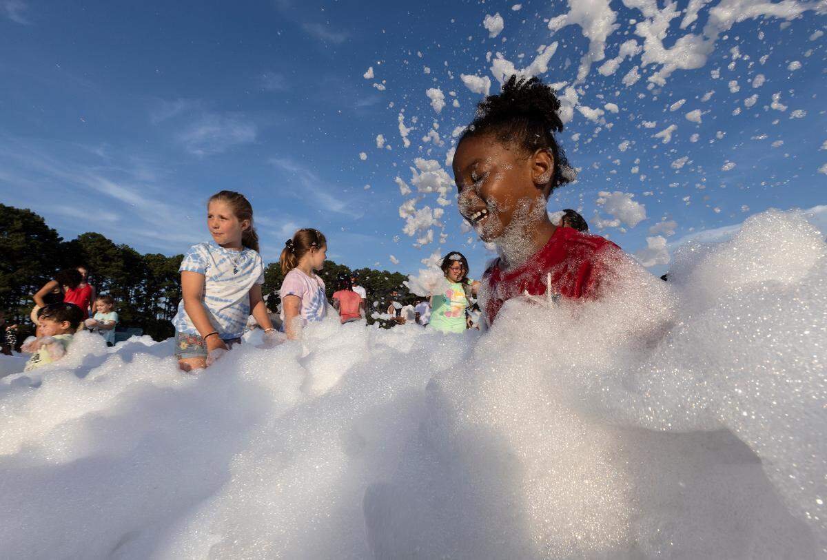 Alani McGuire, 5, laughs while playing in a foam pit during an Independence Day celebration at Dorothea Dix Park on Tuesday, July 4, 2023, in Raleigh, N.C.