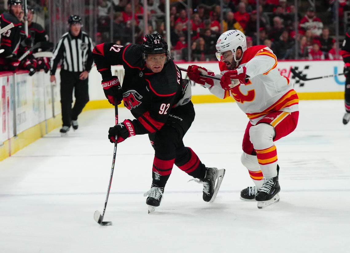 Mar 10, 2024; Raleigh, North Carolina, USA; Carolina Hurricanes center Evgeny Kuznetsov (92) tries to control the puck against Calgary Flames right wing Matt Coronato (27) at PNC Arena. Mandatory Credit: James Guillory-USA TODAY Sports