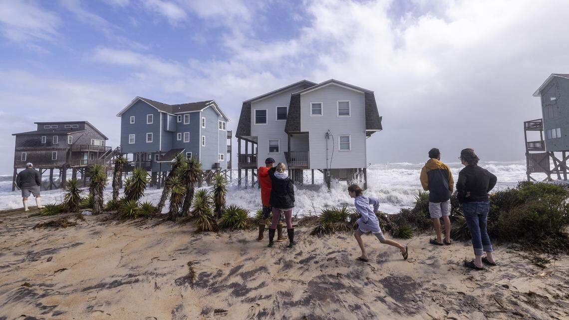 Onlookers watch as rough surf pounds beach homes during high tide on Sunday, Oct. 12, 2025, in Buxton during a nor’easter. Collapsing homes have drawn a lot of attention, but they are a tiny fraction of what’s available in vacation rentals at the Outer Banks.  