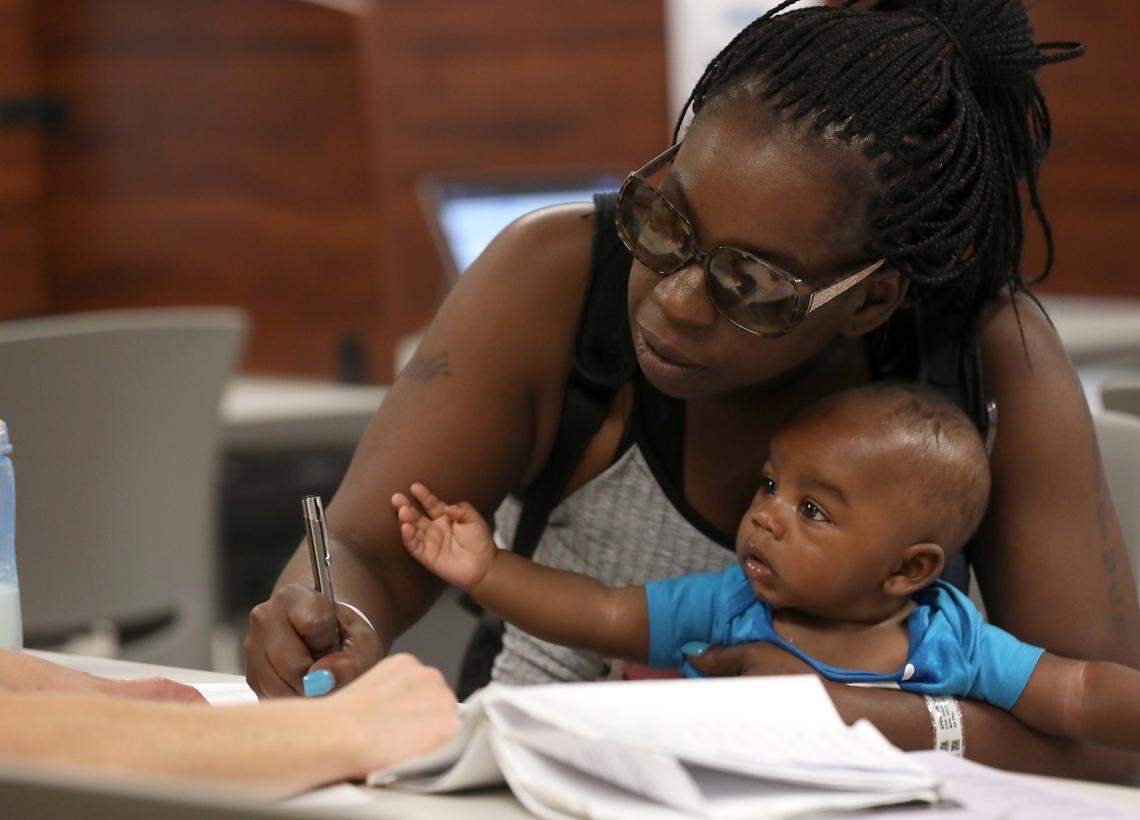 Keosha Spencer holds her son, Lavonte Hinton, while completing paperwork at the Wake County Legal Support Center on Tuesday, May 16, 2023, in Raleigh, N.C. The center provides free assistance to those filing legal documents pro se.