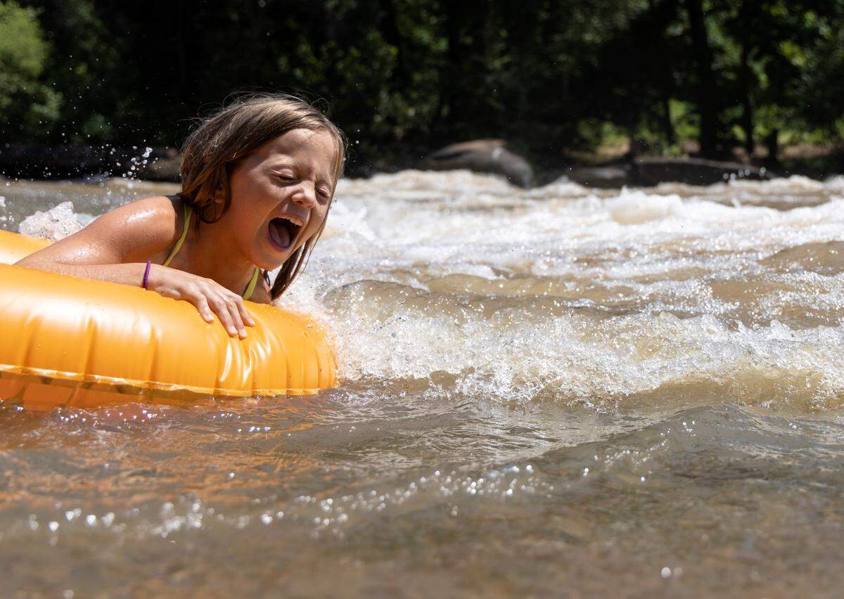 A child lets out a squeal of delight while tubing through rapids at RiverPark at Cooleemee Falls on Saturday, Aug. 5, 2023, in Woodleaf, N.C.