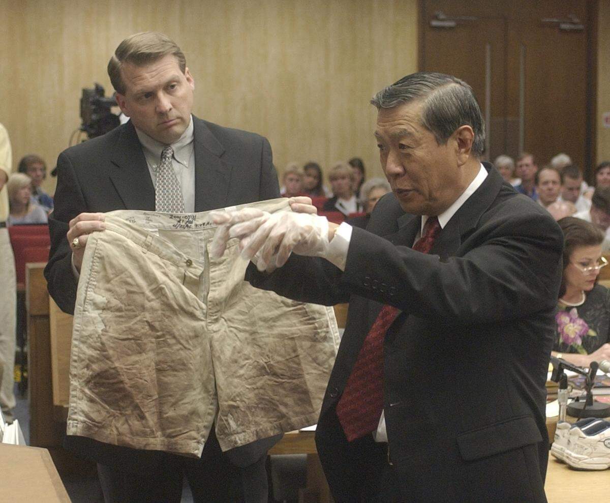 Forensic scientist and blood spatter expert Henry C. Lee, right, dons his latex gloves in front of the jury, he says because he does not want his DNA on the evidence while handling the blood stained shorts of Michael Peterson, left, held by prosecutor Jim Hardin during the cross-examination of the defense witness at Michael Peterson’s murder trial.