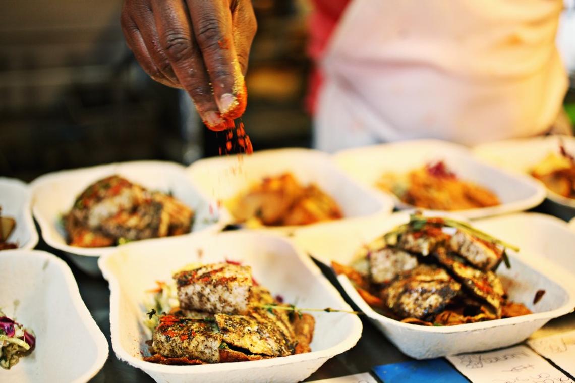 Durham chef Ricky Moore, owner of the Saltbox Seafood Joint in Durham, tops orders with spices while adding finishing touches to each dish in 2016.