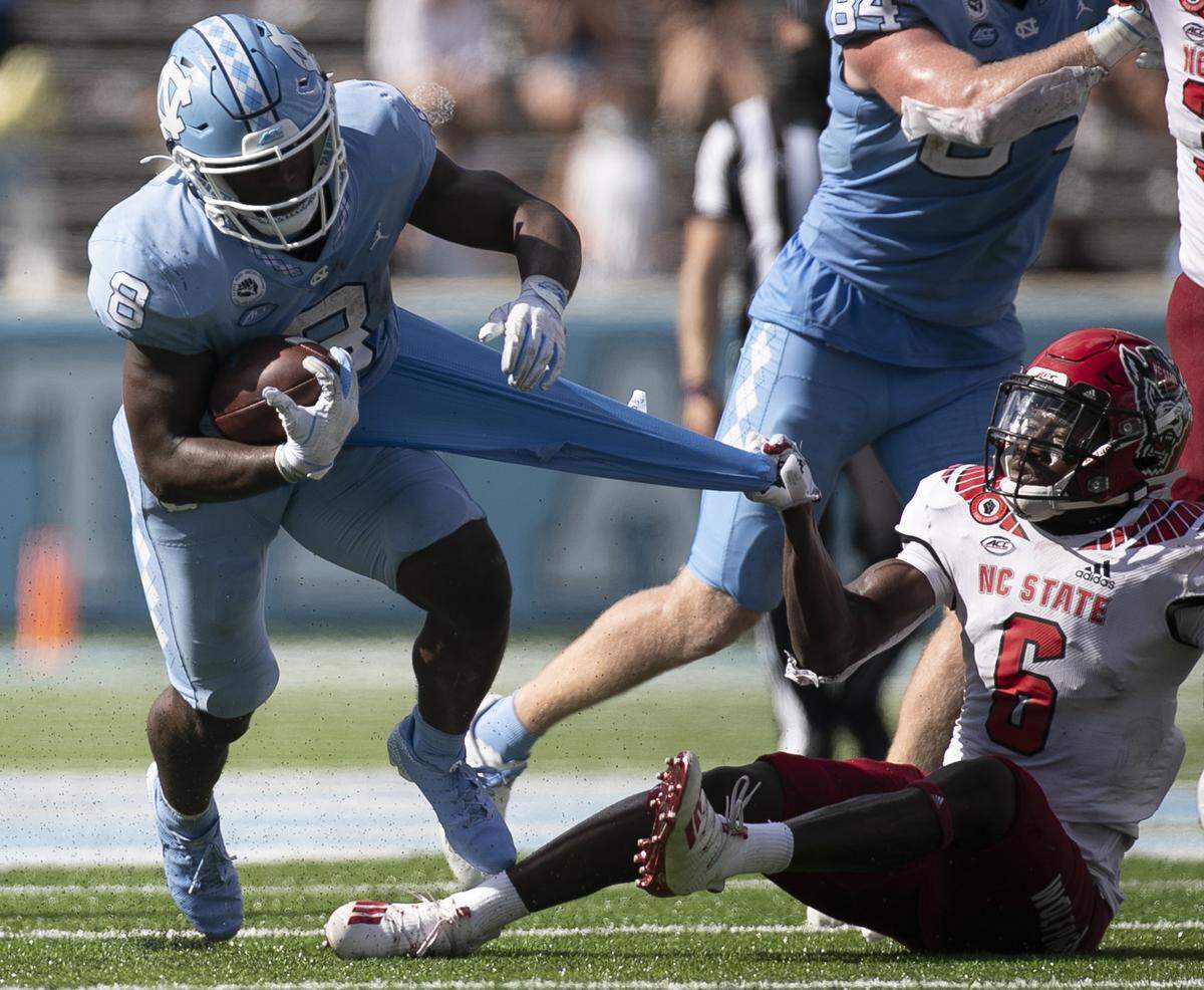 N.C. State’s Jakeen Harris (6) tries to stop North Carolina’s Michael Carter (8) after a 12-yard gain in the third quarter at Kenan Stadium on Saturday, October 24, 2020 in Chapel Hill, N.C.