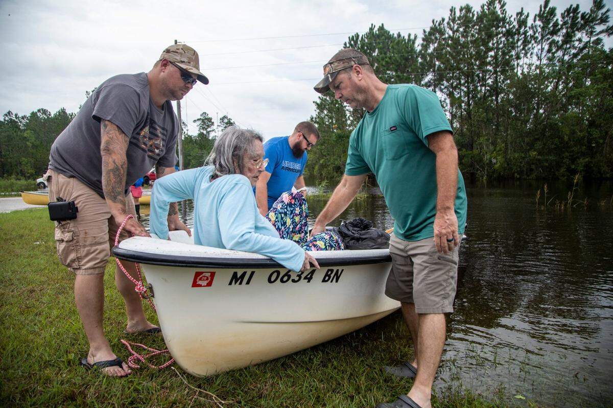 Cody Guillory, left, and Jeff Delle help 80-year-old Eileen Delle onto dry land Monday, Aug. 30, 2021 after floodwaters from Hurricane Ida surrounded her elevated home in the Shoreline Park community in Bay St. Louis.