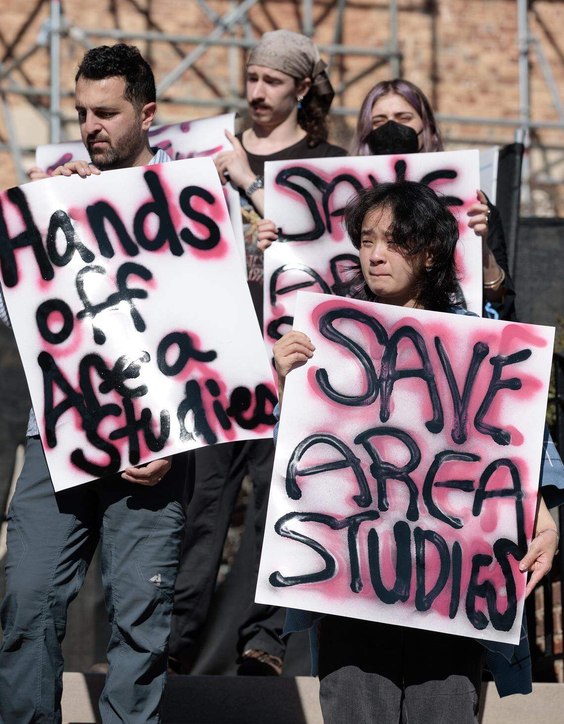 People hold signs near South Building at UNC-Chapel Hill on Wednesday, Jan. 7, 2026, during a protest held in response to the potential closure of six university study centers that focus on international history, politics and cultures.
