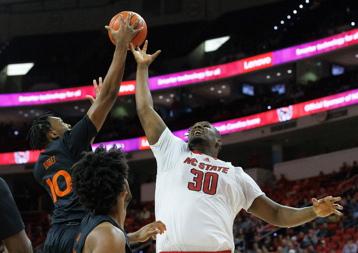 Miami’s Paul Djobet grabs a rebound away from N.C. State’s DJ Burns Jr. during the first half of the Wolfpack’s game on Tuesday, Jan. 30, 2024, at PNC Arena in Raleigh, N.C.